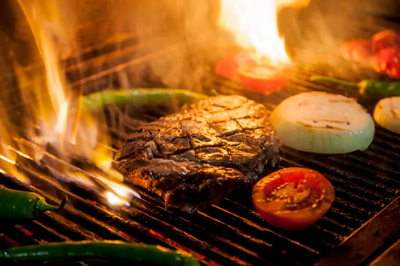 Arrachera asándose a la flama con cebolla, tomate y chiles
