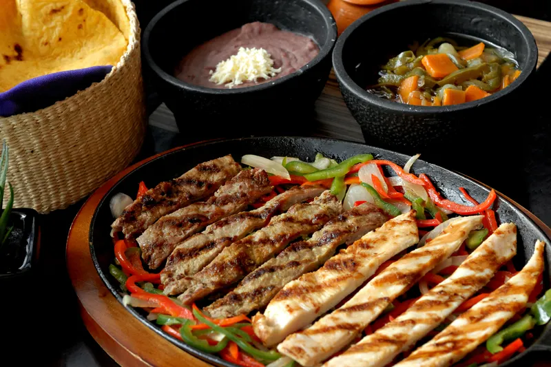 Parrillada de carne y pollo con pimientos, frijoles y tortillas