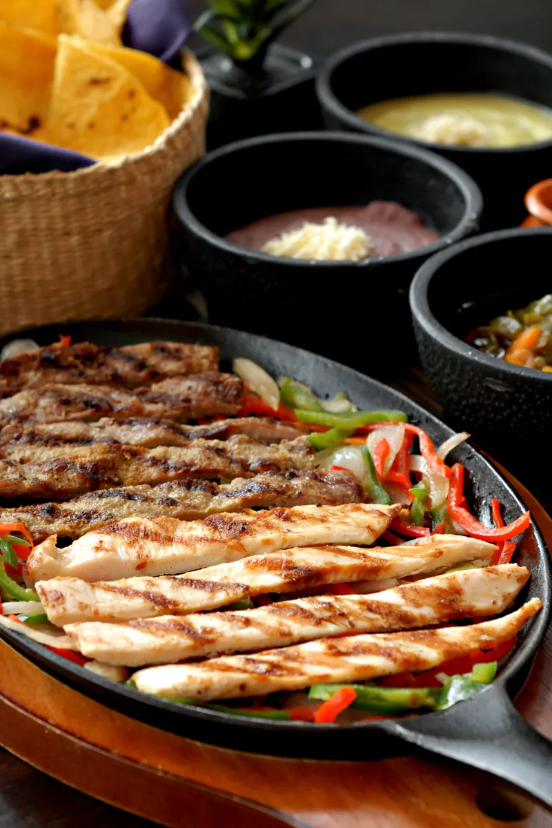 Fajitas de res y pollo en plancha con frijoles, salsas y totopos para compartir